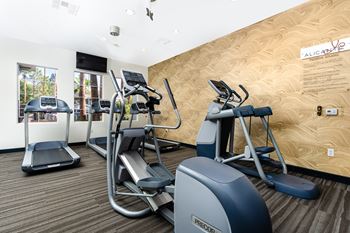 A gym with a treadmill, elliptical trainer and a stationary bike.